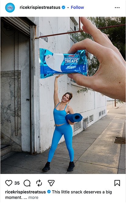 A woman in blue workout gear looking like she's holding up a giant Rice Krispies Treat over her head.